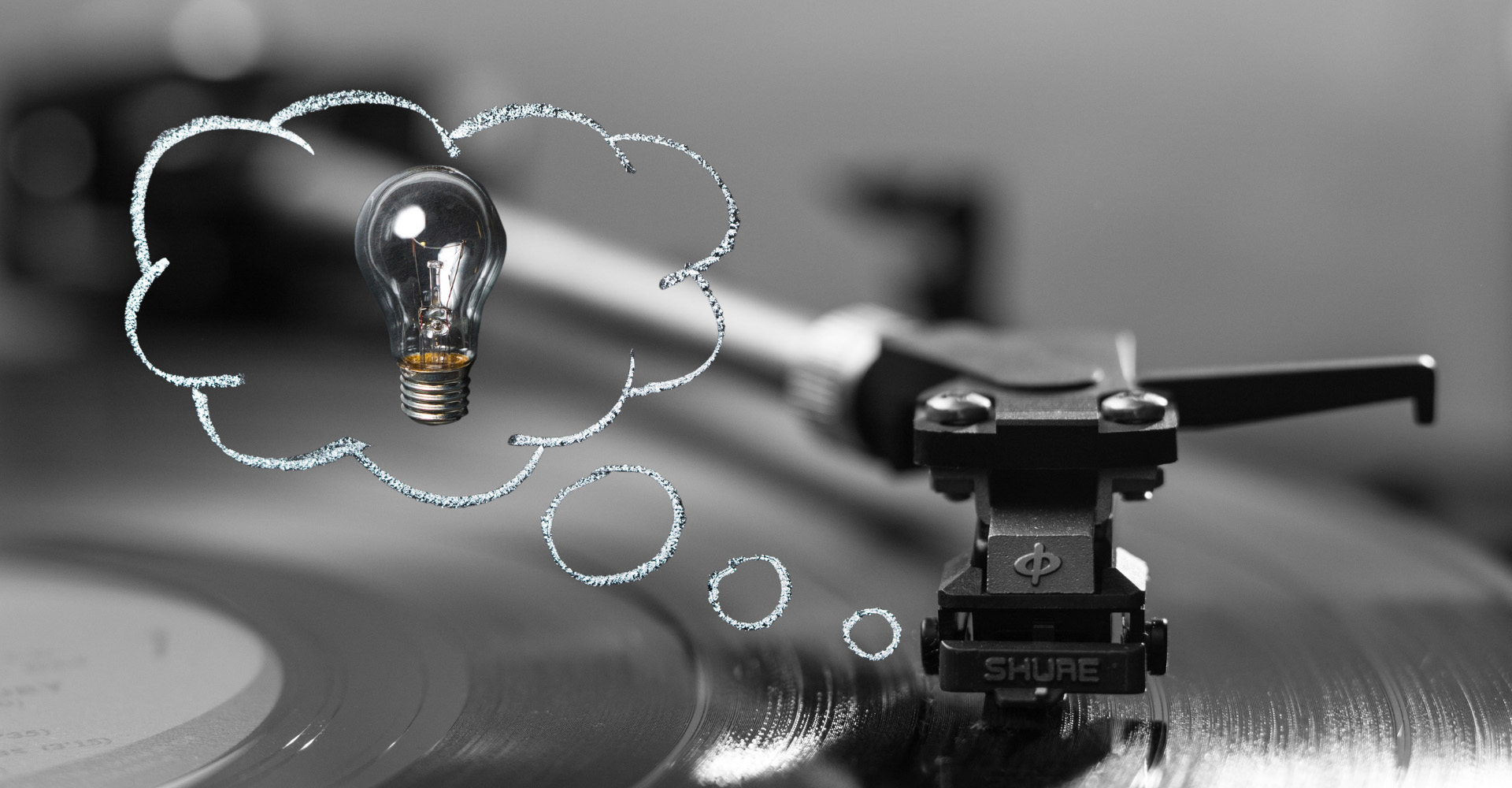 Close-up image of a record player showing the needle arm playing a record, with a chalk line drawing of a lightbulb superimposed on the image.