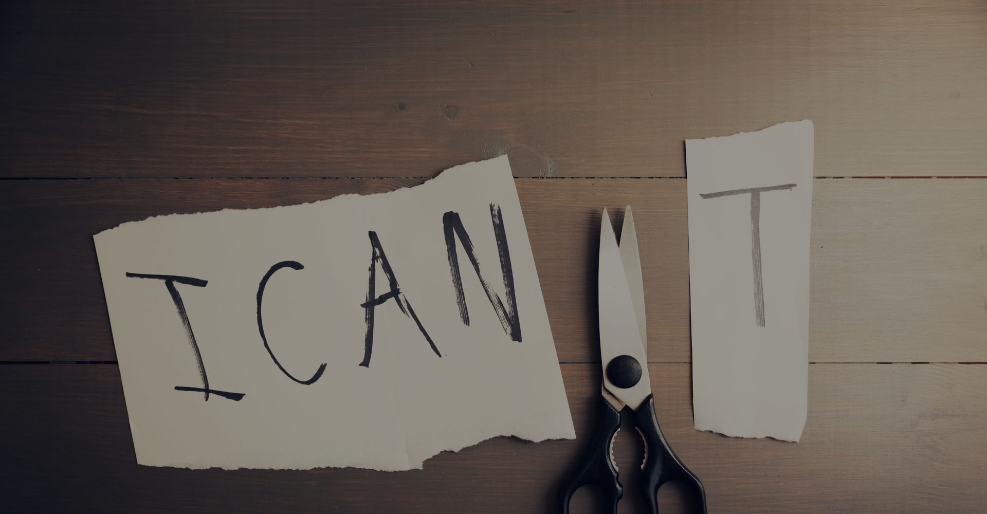 A piece of paper with a scissor visible where cut through the phrase 'I CAN'T' to change to to 'I CAN'