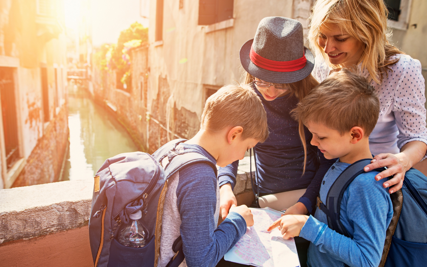 Three children and their guardian gathered around a map overlooking an old canal