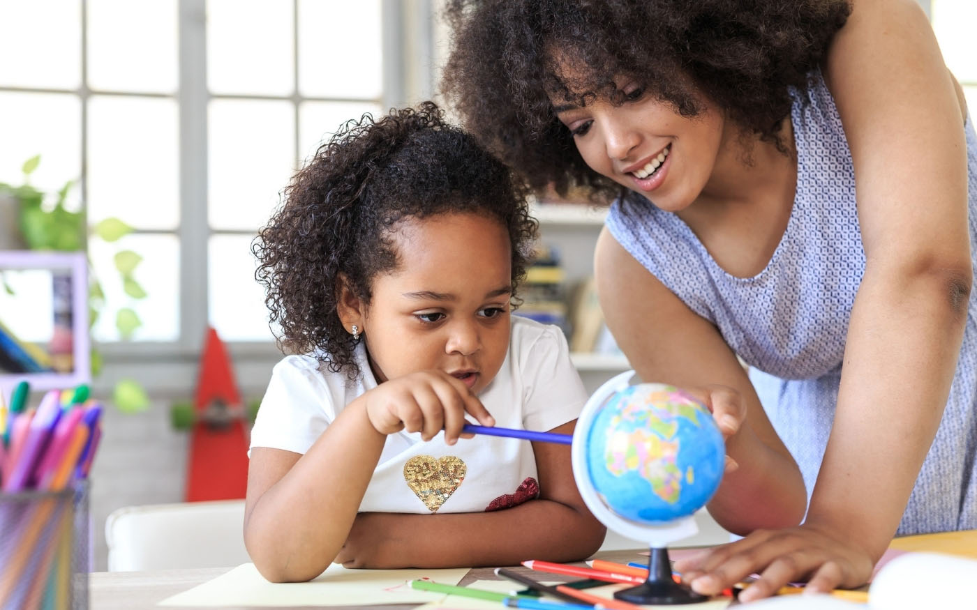 A mother and child looking at a globe