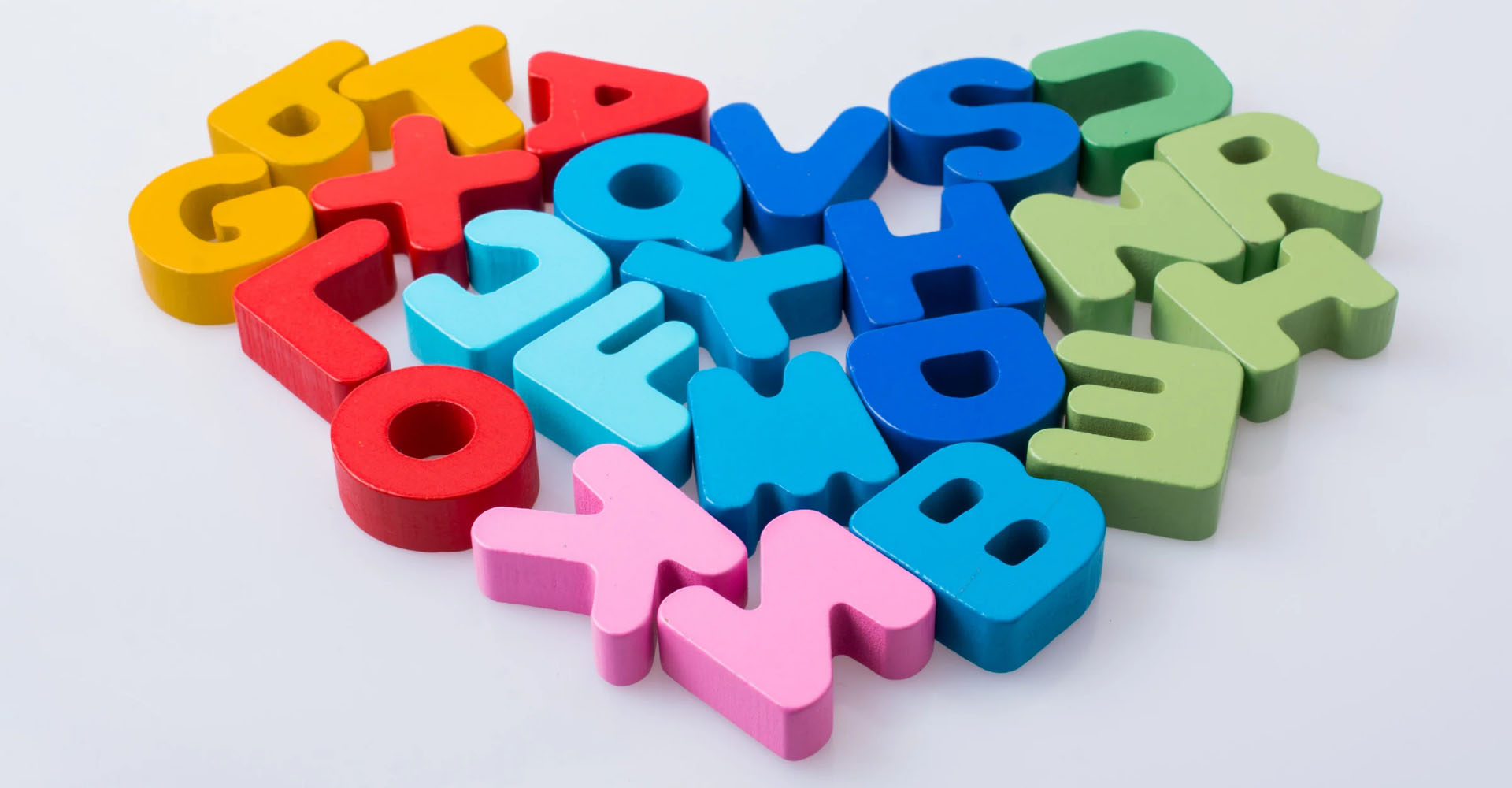 Children's plastic fridge letter magnets arranged jumbled together into a heart shape.