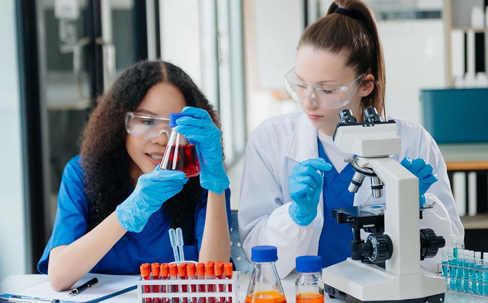 Two women taking interest in each others work in the chemistry lab.